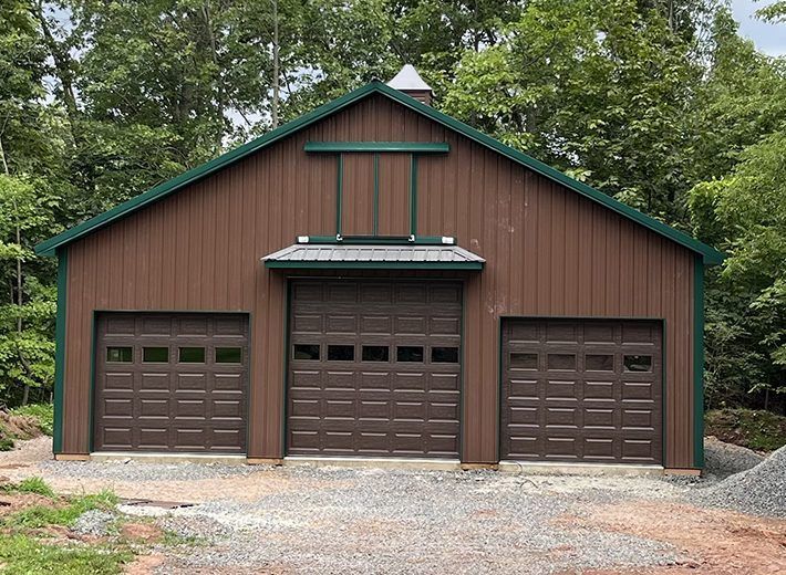 A brown garage with three garage doors and a green roof