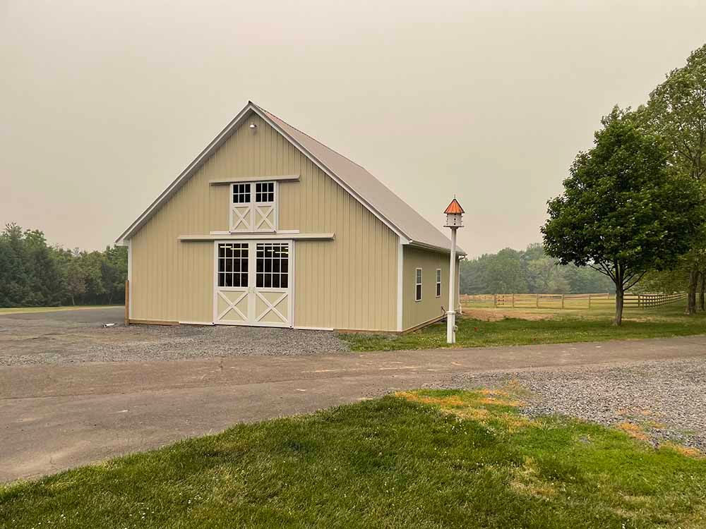 A large barn is sitting in the middle of a grassy field.