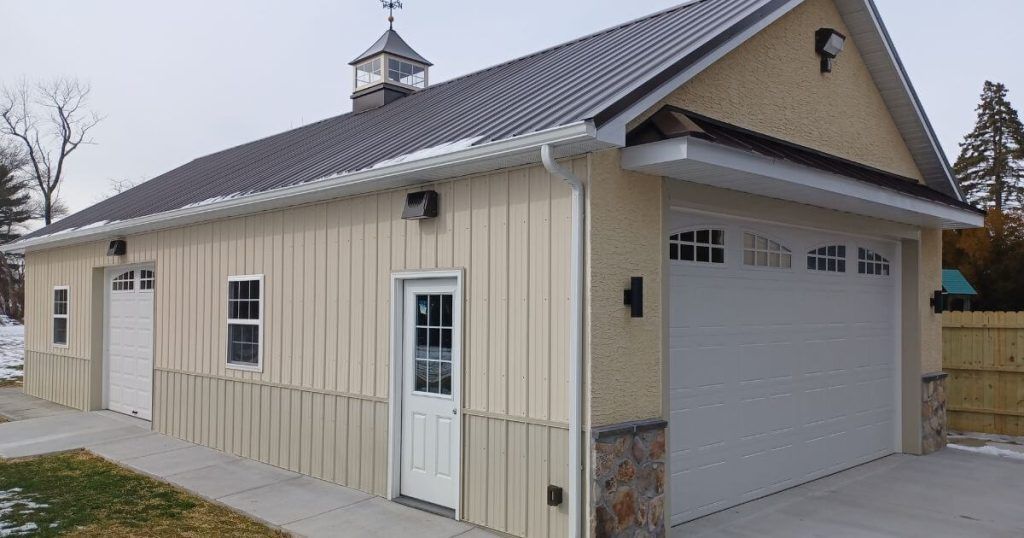 A large garage with two garage doors and a weather vane on the roof.