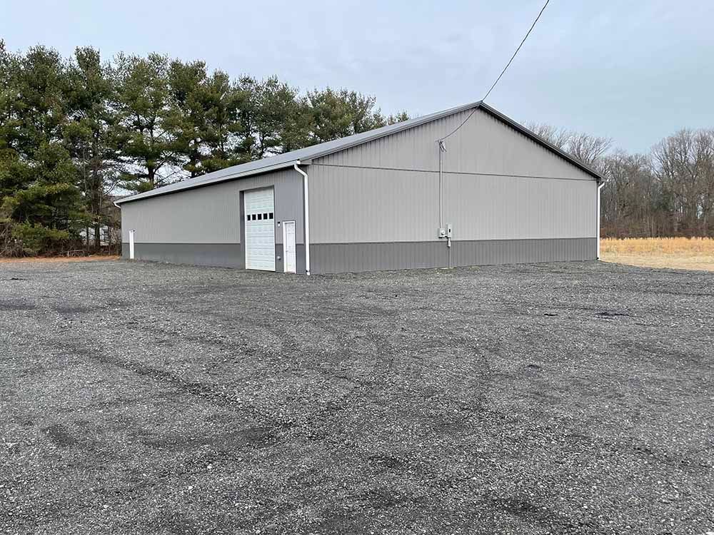 A large building is sitting in the middle of a gravel lot.