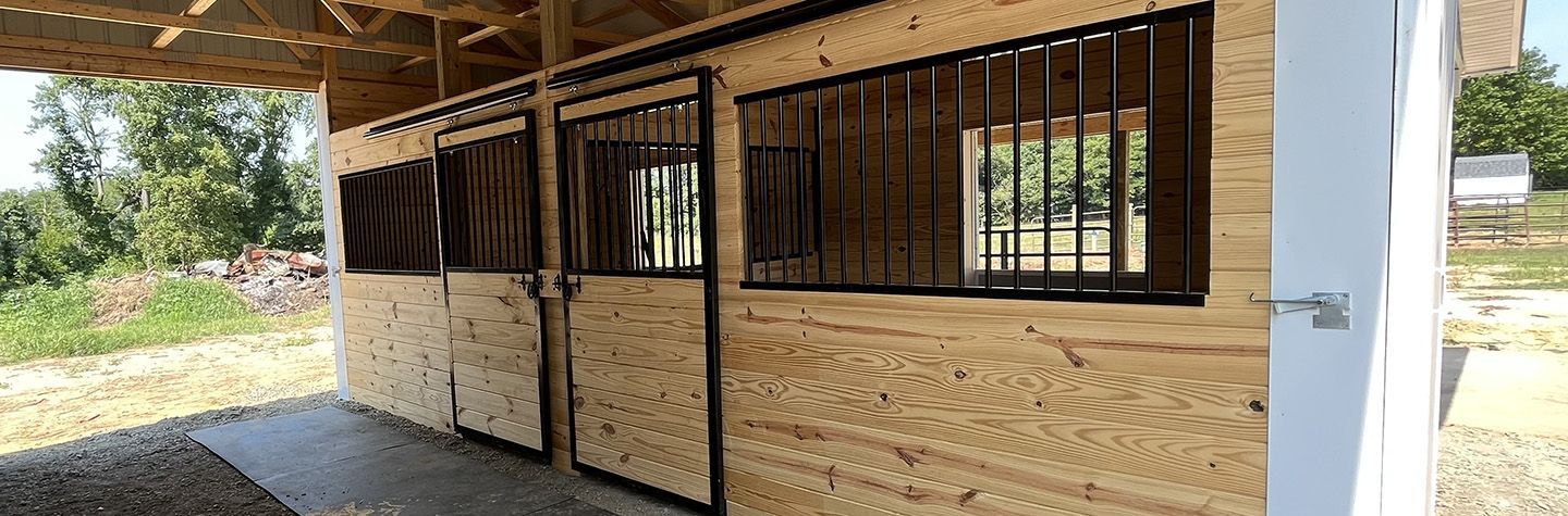 A wooden stable with a white door and windows.