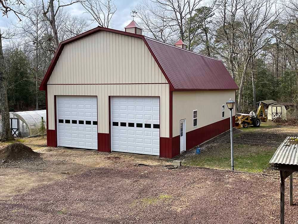 A barn with two garage doors and a red roof.
