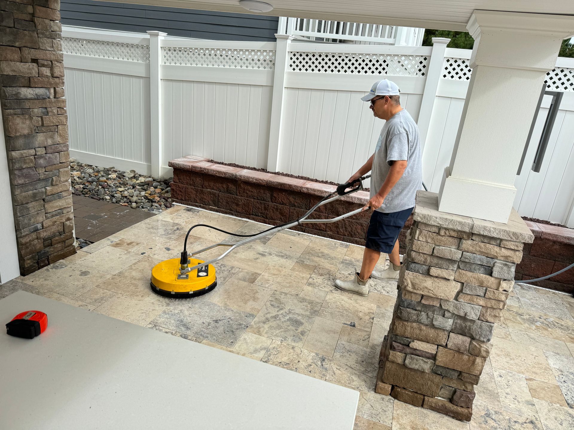 A man is cleaning a patio with a machine.