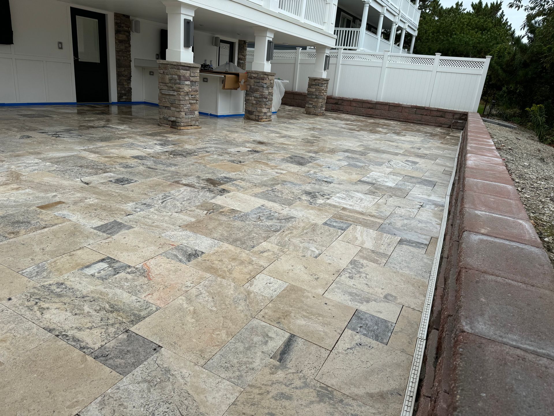 A patio with a brick wall and a white building in the background.