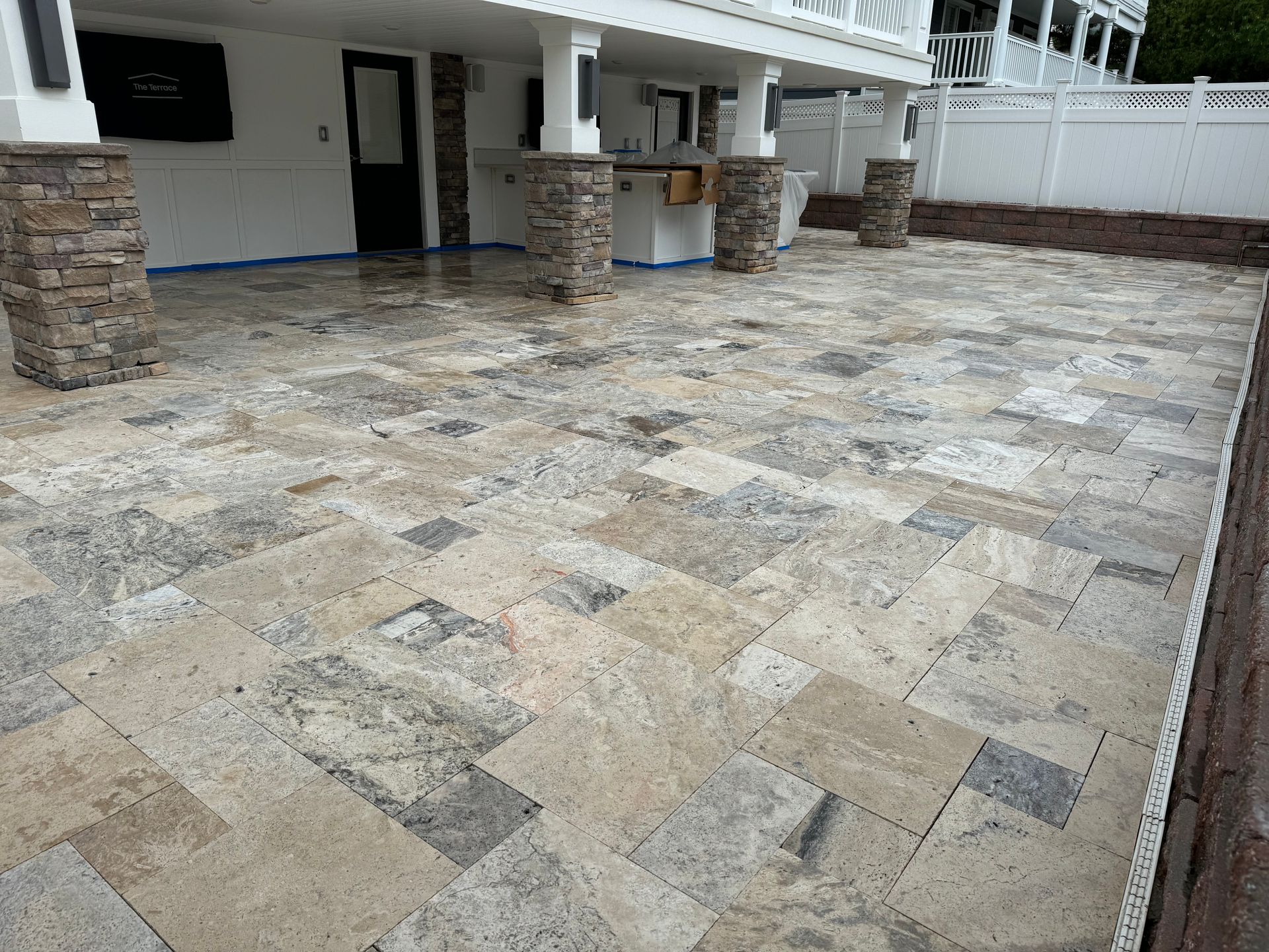 A patio with a lot of tiles and pillars in front of a house.