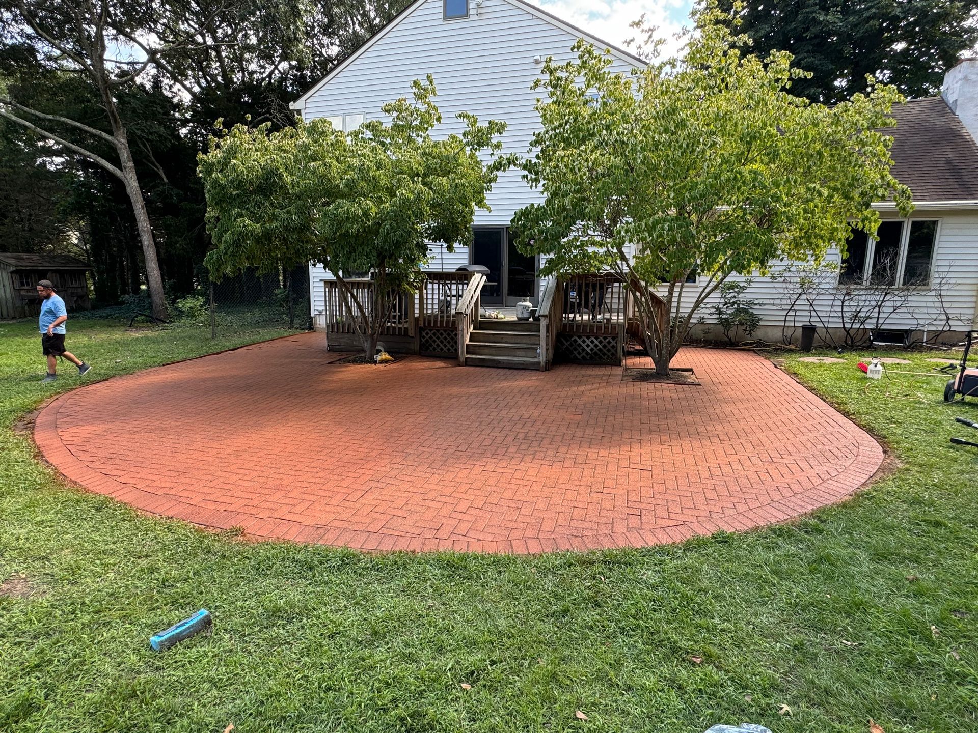 A man is walking around a brick patio in front of a house.