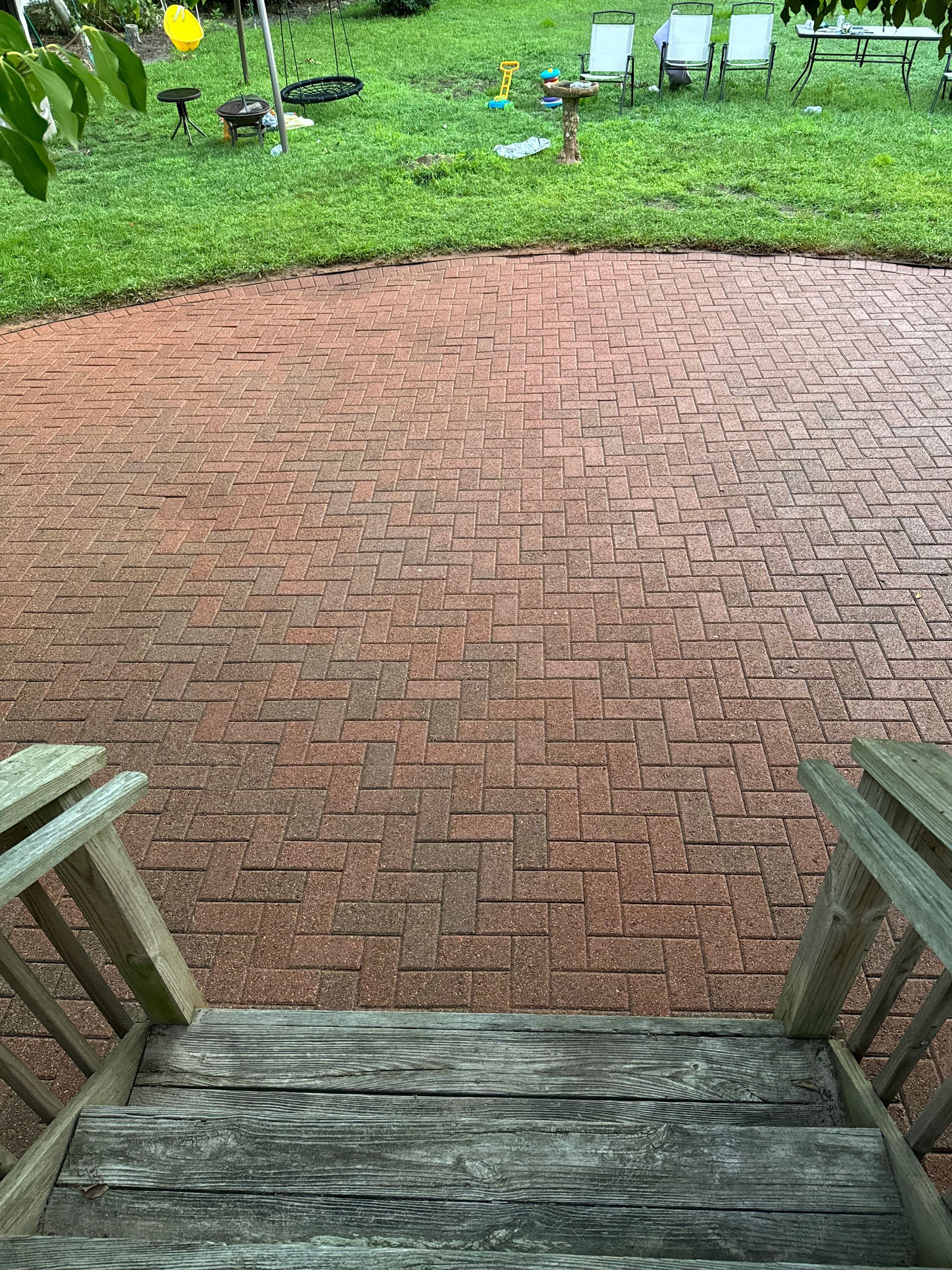 A wooden deck with stairs leading up to a brick patio.