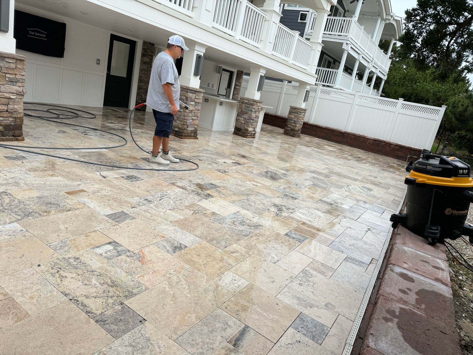 A man is cleaning a patio with a vacuum cleaner.
