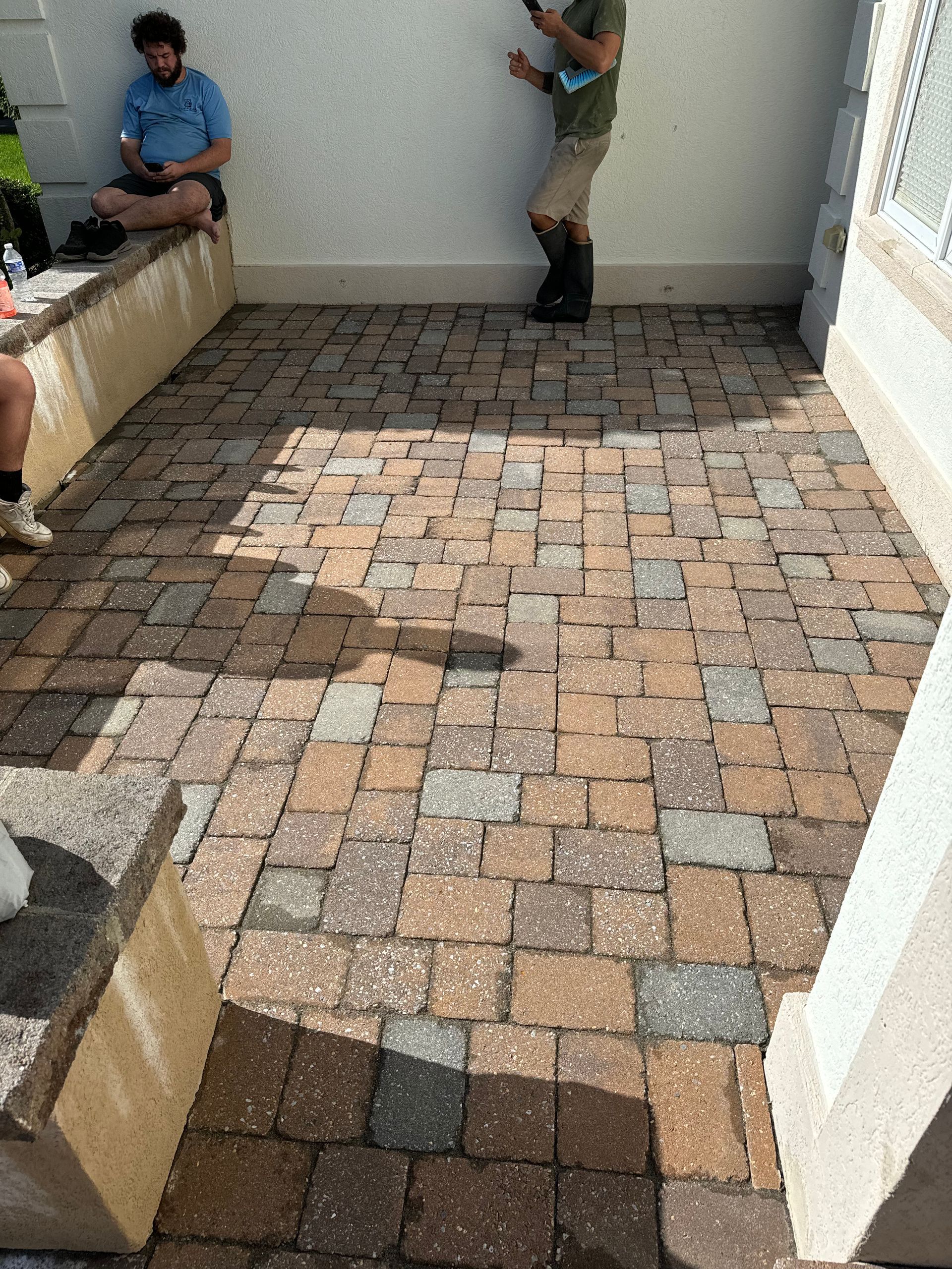 A group of people are sitting on a bench on a brick patio