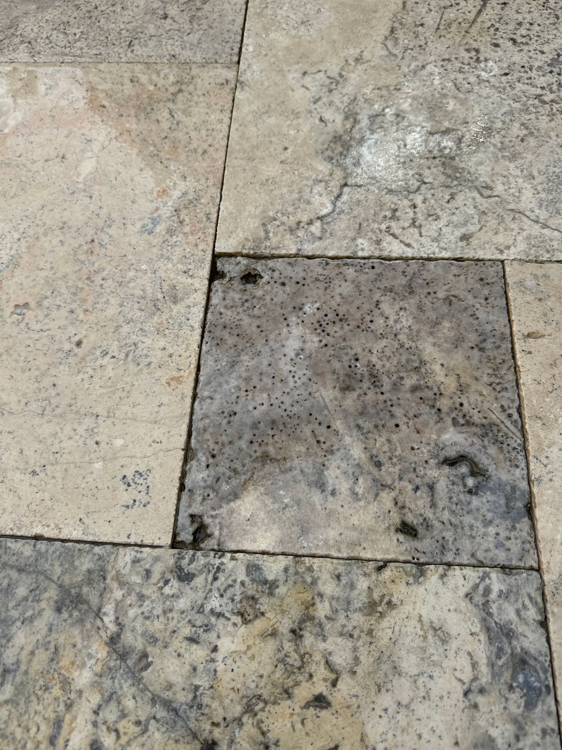 A close up of a tile floor with a gray and white marble texture