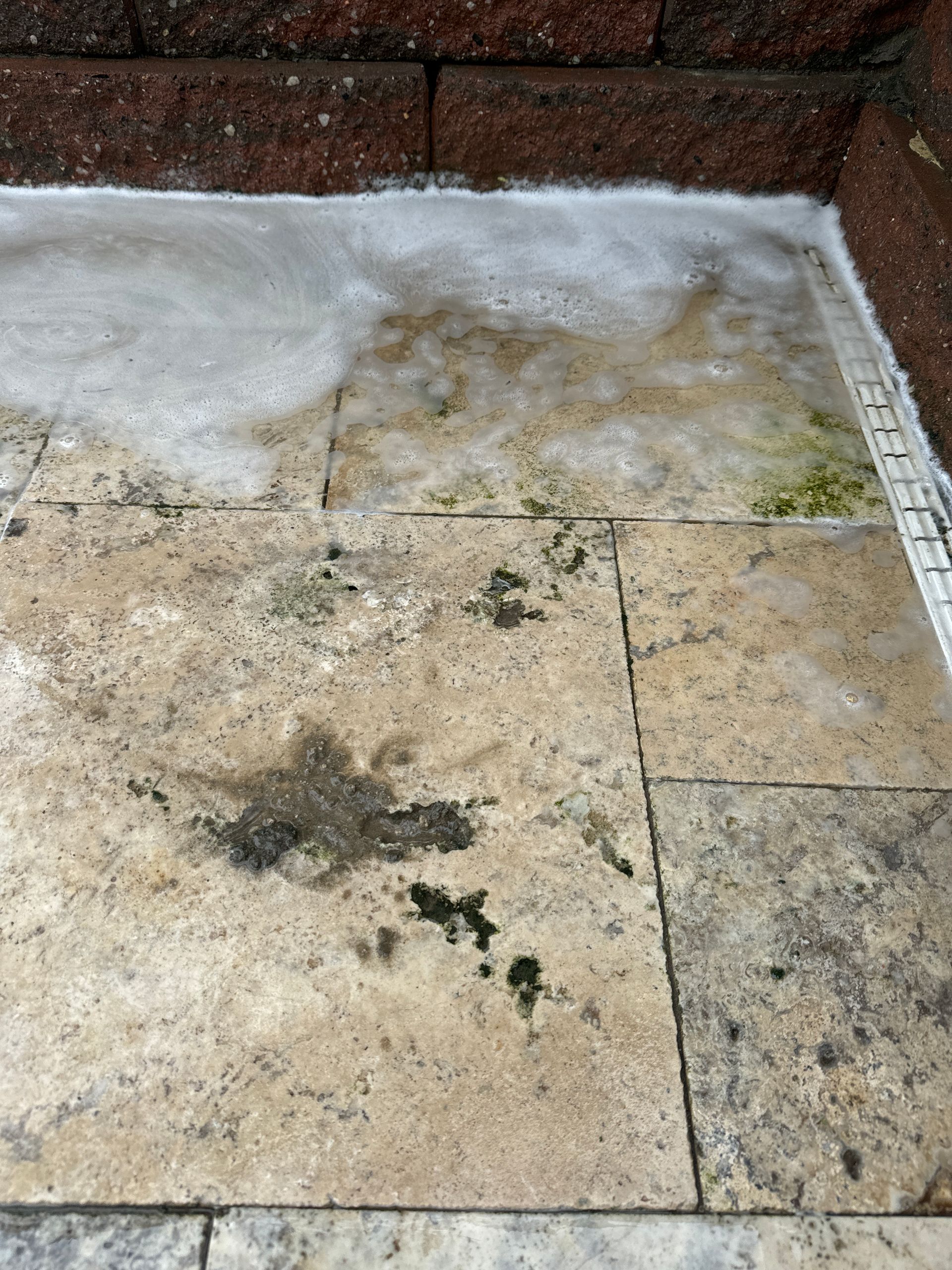 A dirty tile floor with a brick wall in the background.