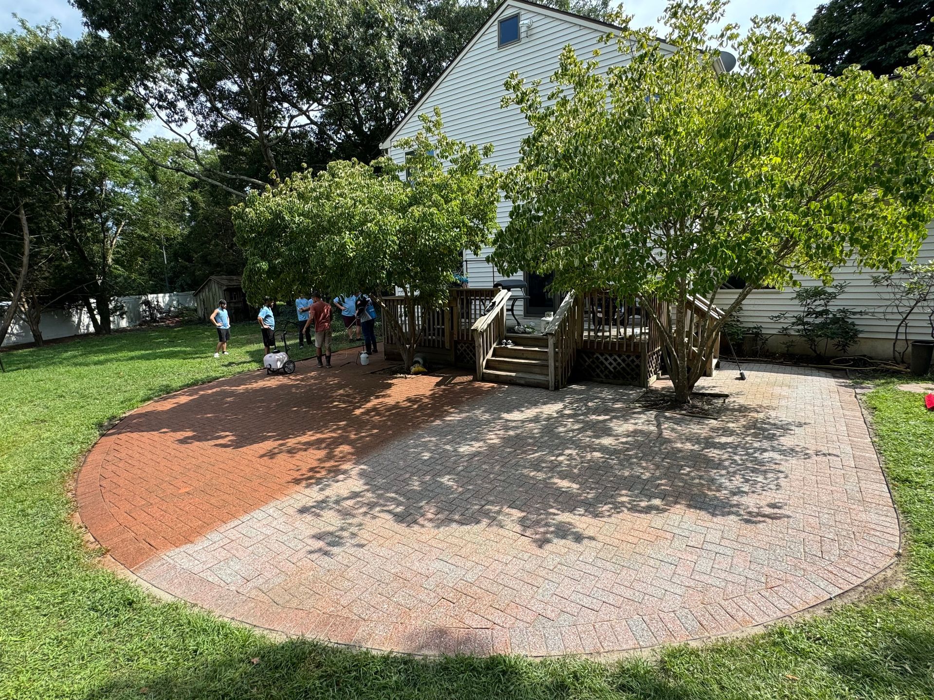 A group of people are standing in a circle in the grass in front of a house.