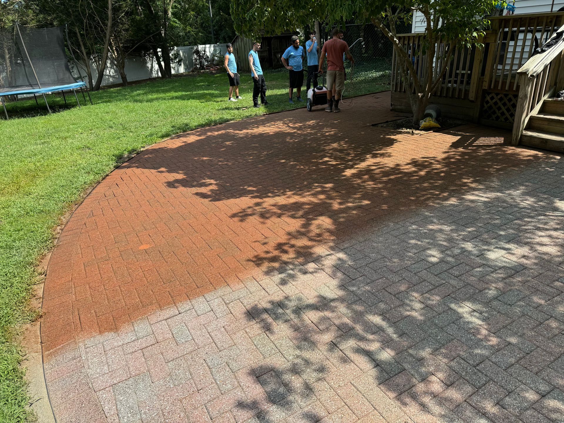 A group of people are standing on a brick walkway in a yard.