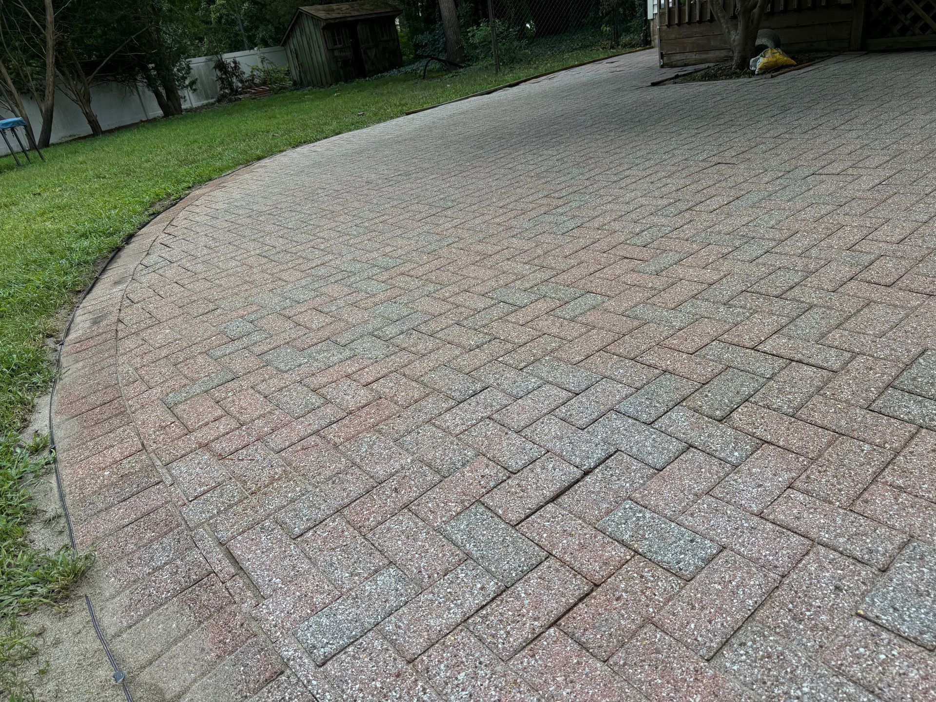A brick walkway leading to a lush green yard.