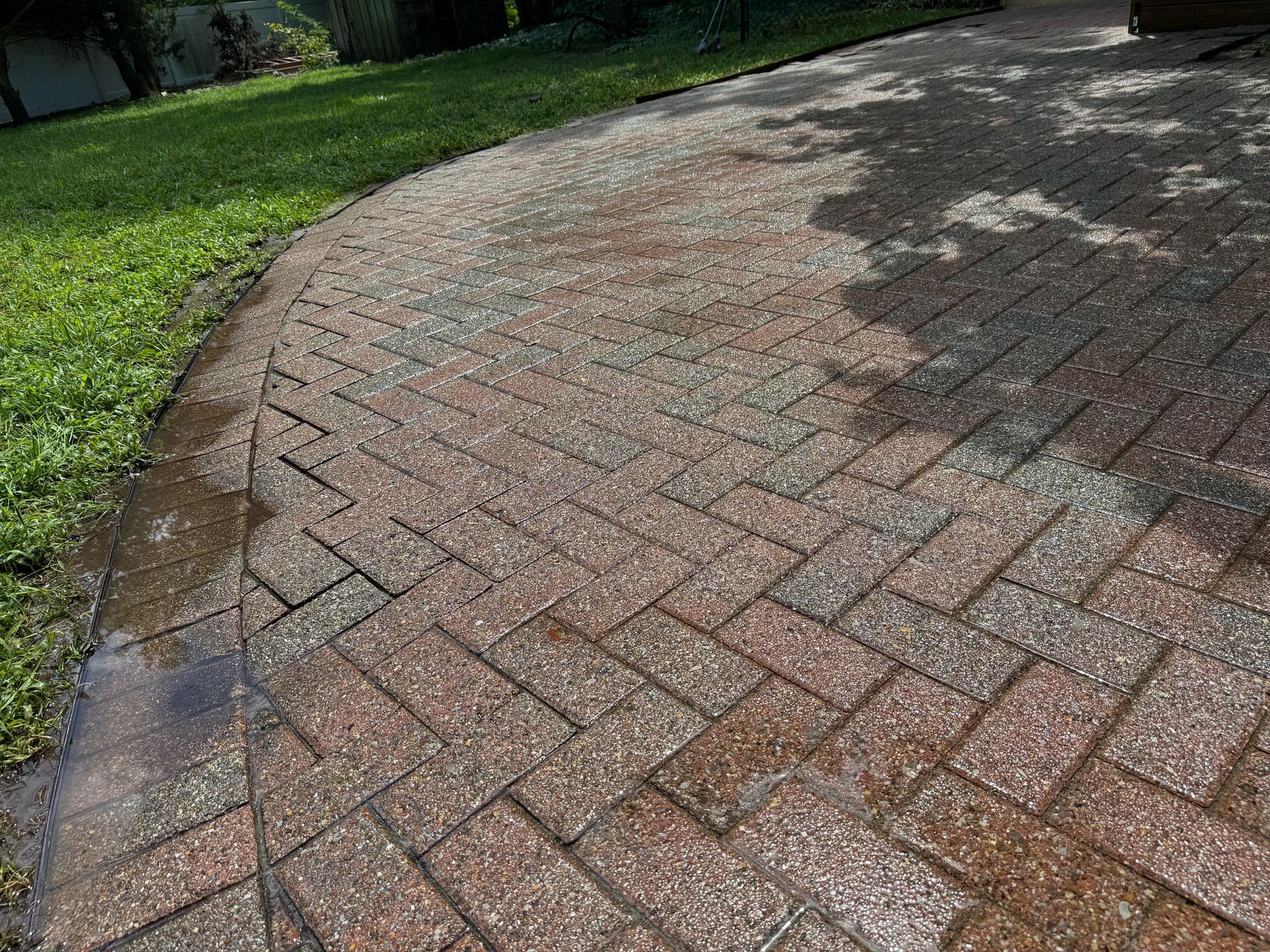 A brick walkway is being cleaned with a pressure washer.