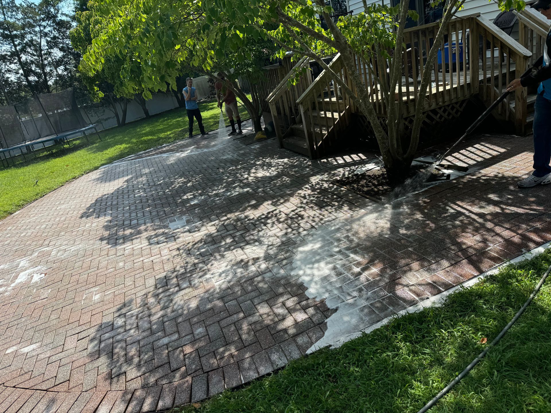 A person is cleaning a brick walkway with a high pressure washer.