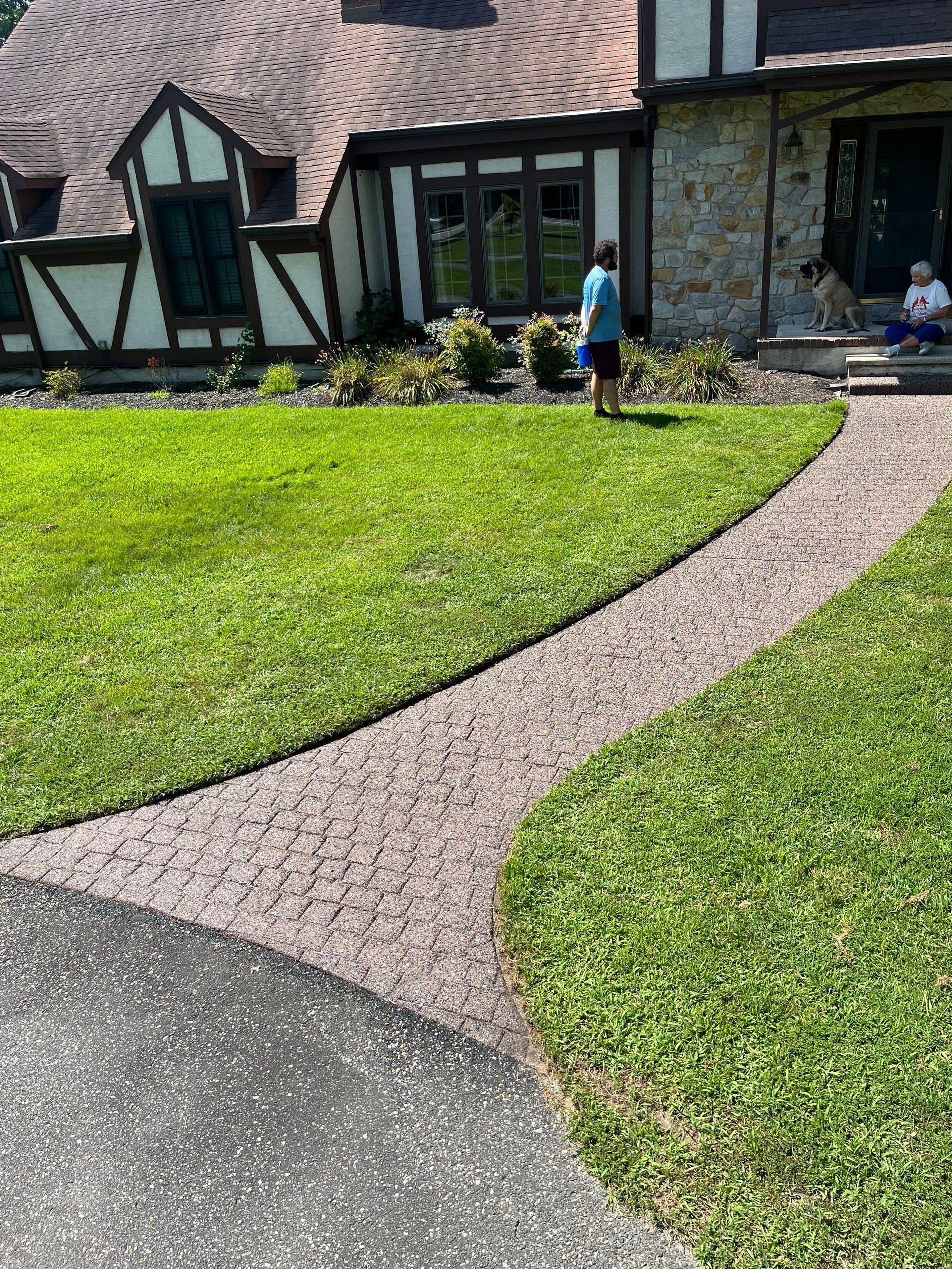 A man is walking a dog down a path in front of a house.