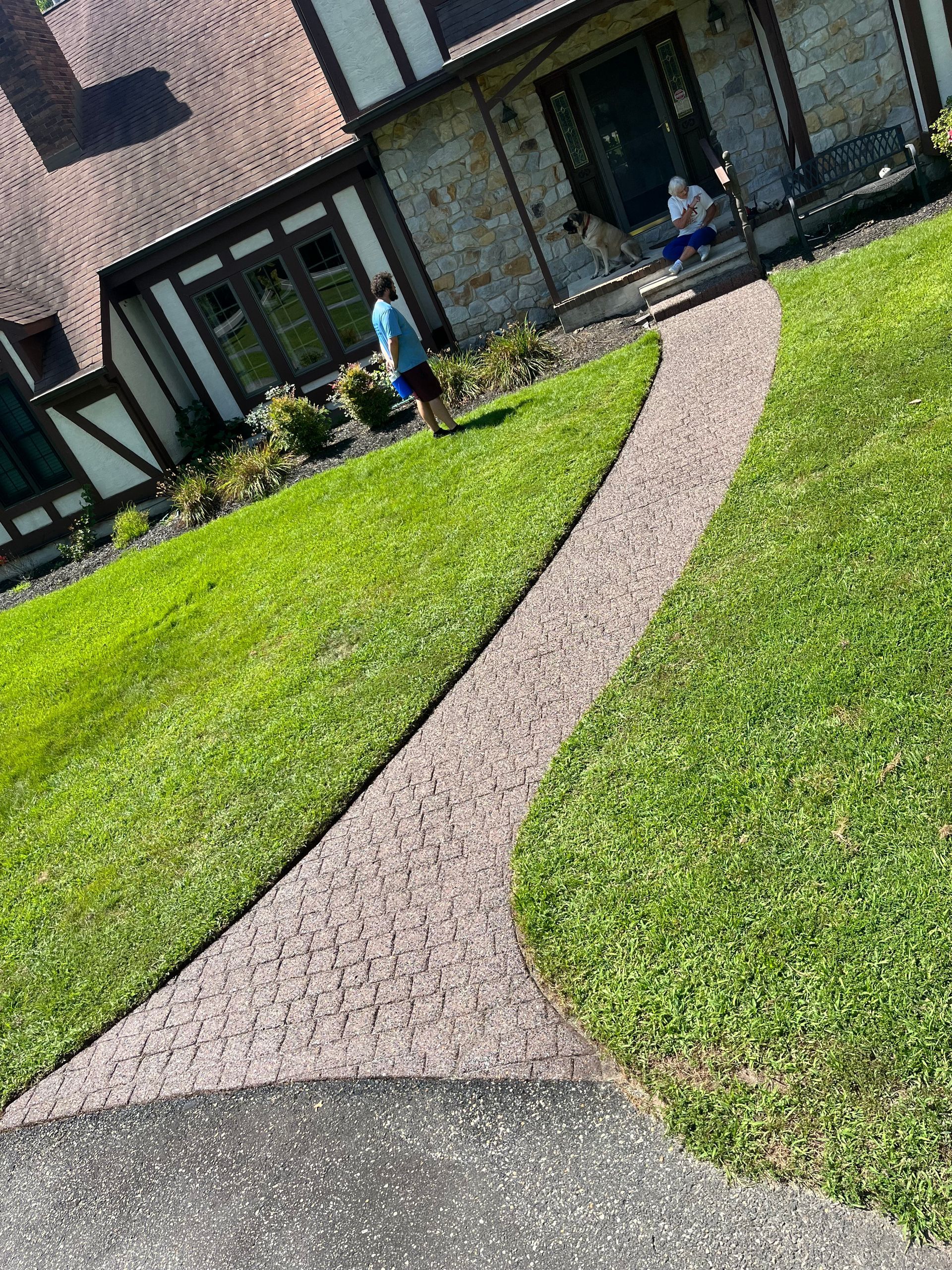 A man is walking down a path in front of a house.