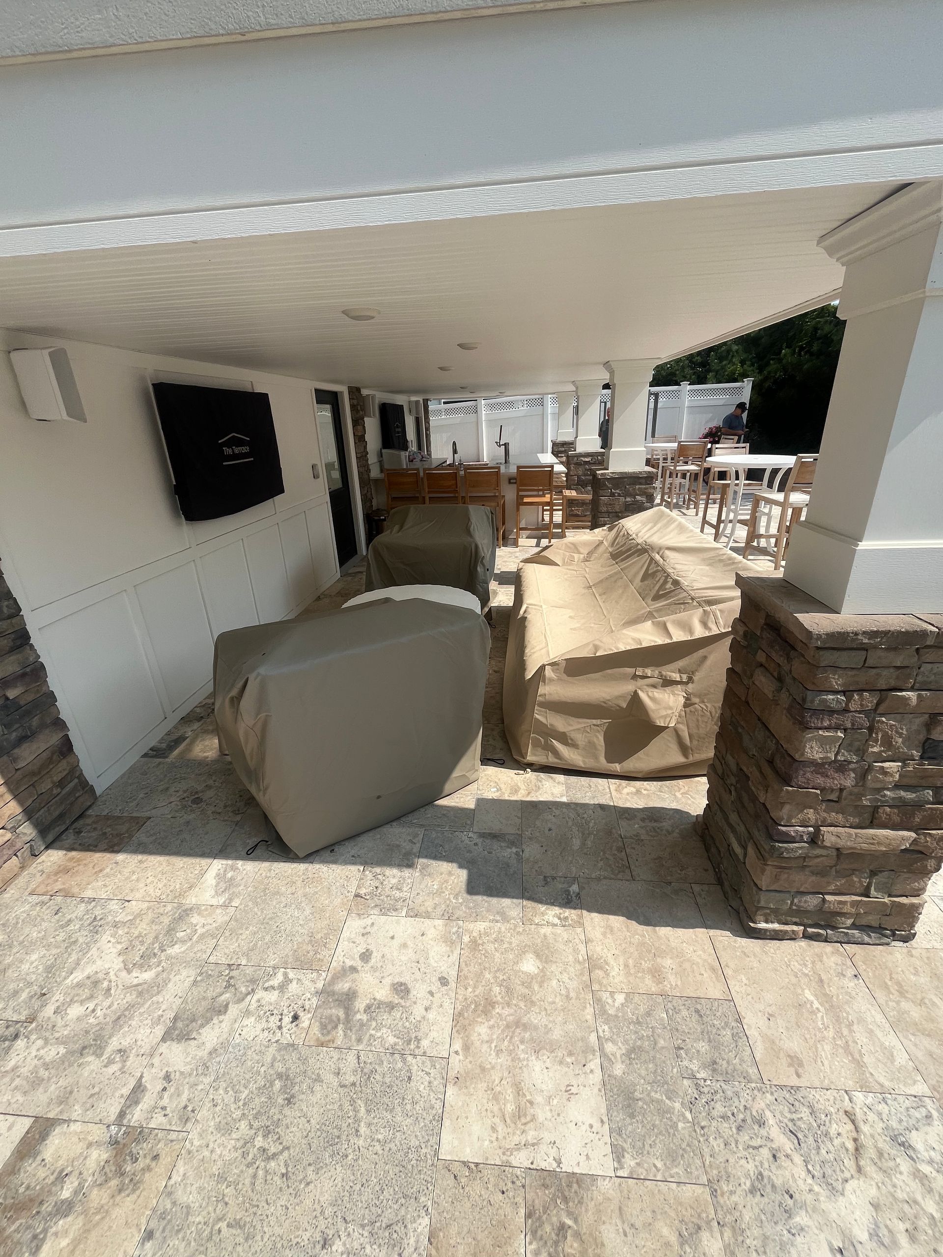 A patio with a lot of furniture and a tv on the wall.