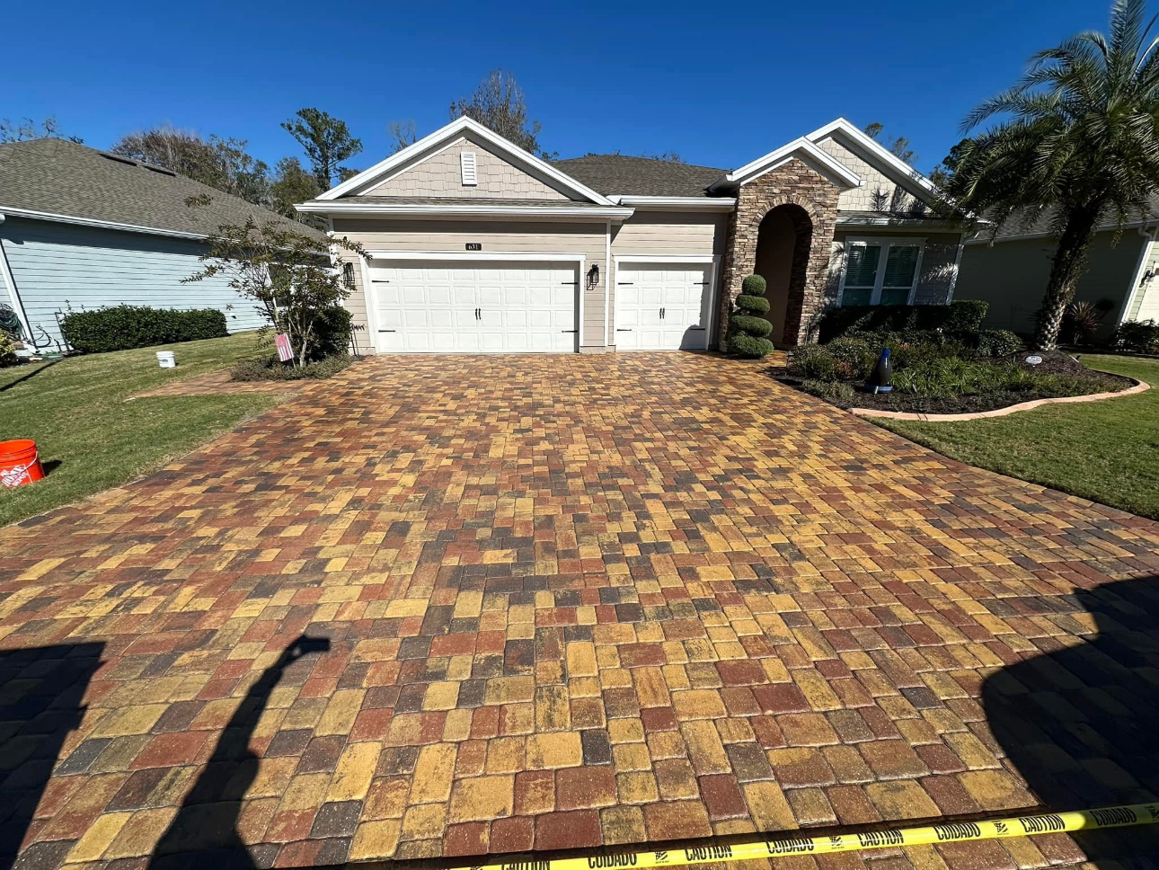 A brick driveway in front of a large house.