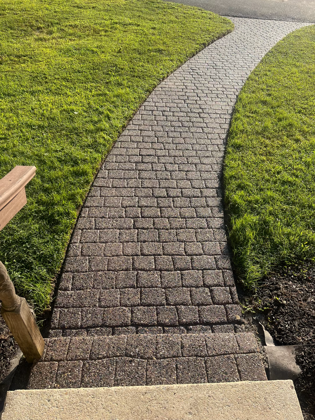 A brick walkway going through a lush green field.