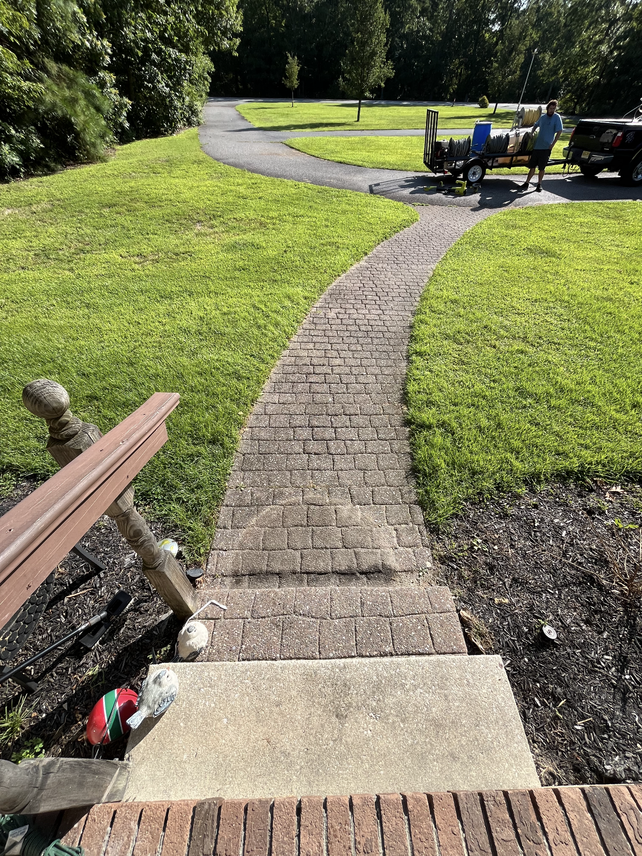A brick walkway leading to a park with people sitting on a bench.