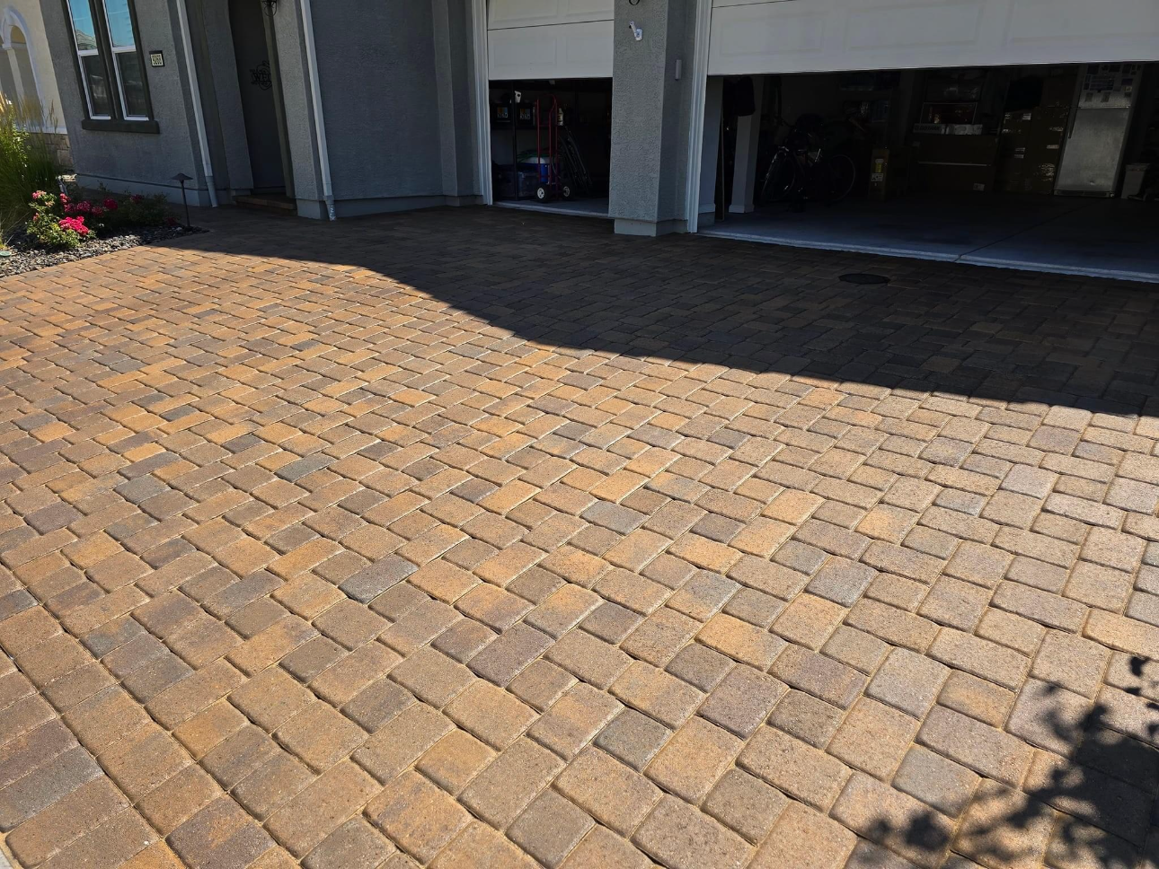 A brick driveway with a garage in the background.