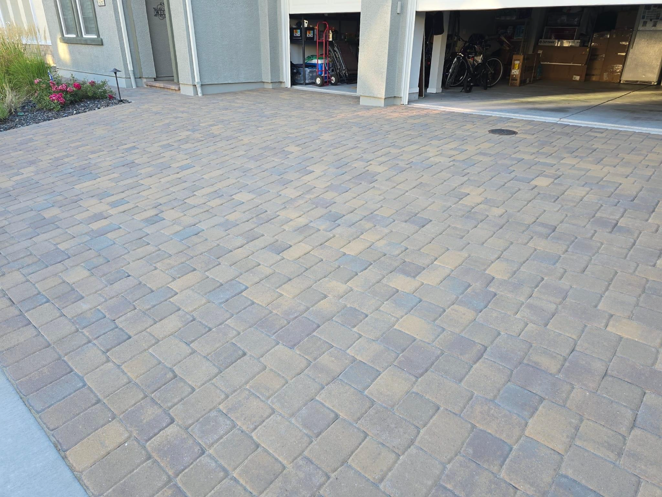 A brick driveway with a garage in the background