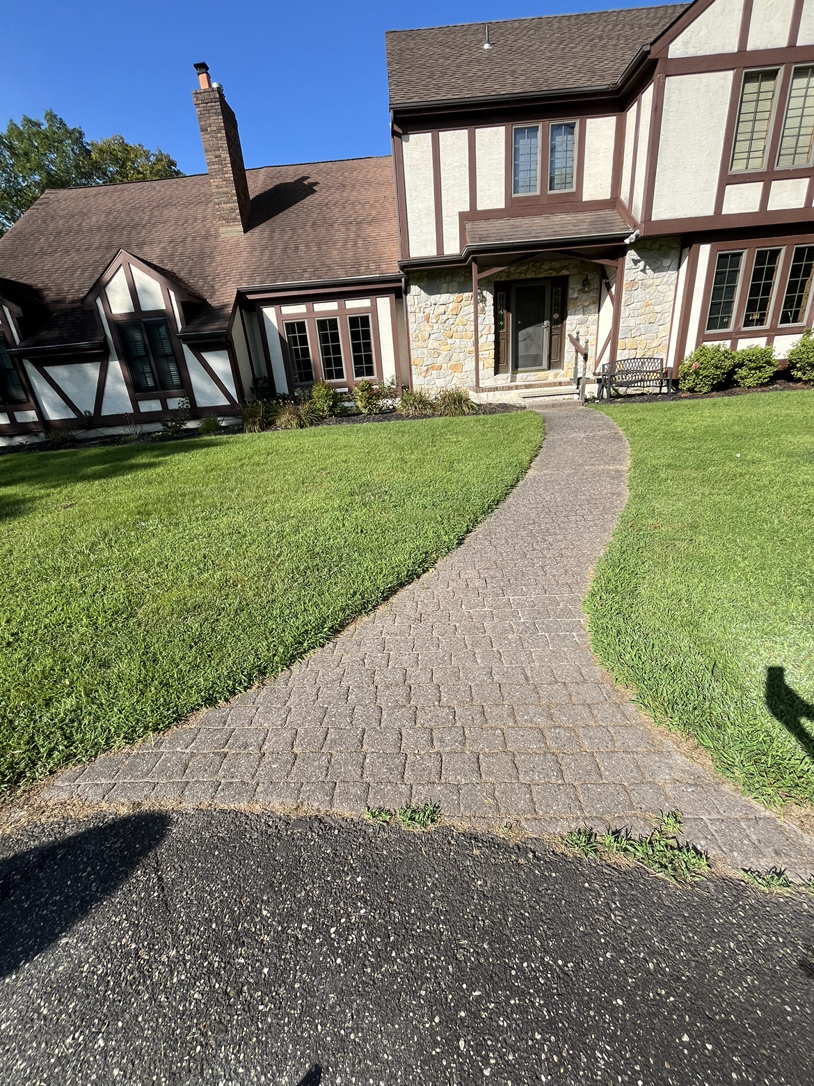 A large house with a walkway leading to it and a lush green lawn.