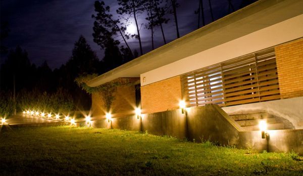 A house is lit up at night with a full moon in the background