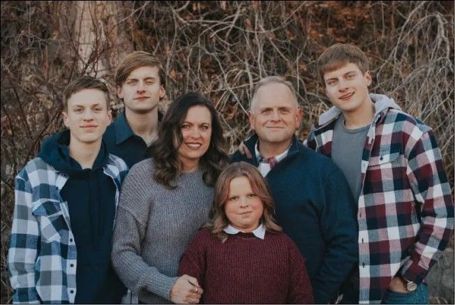 A family posing for a picture together in front of a bush.