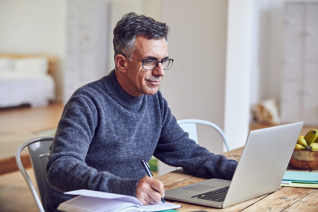A man is sitting at a table using a laptop computer.