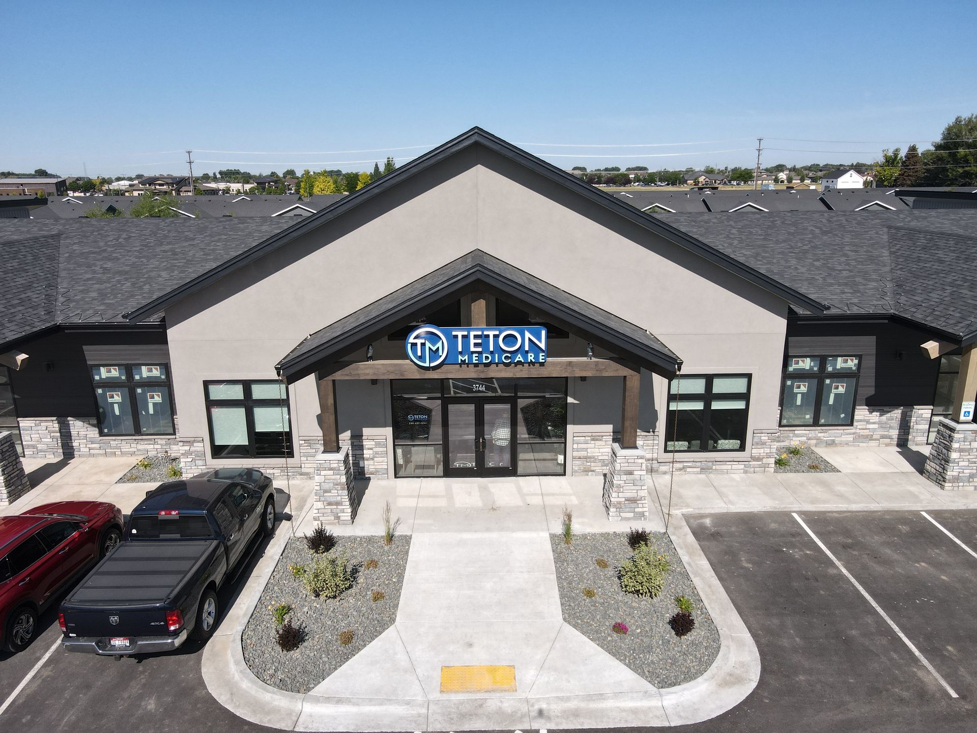 Exterior view of the Teton Financial Group building with a dark grey facade and landscaping, parked cars in front.