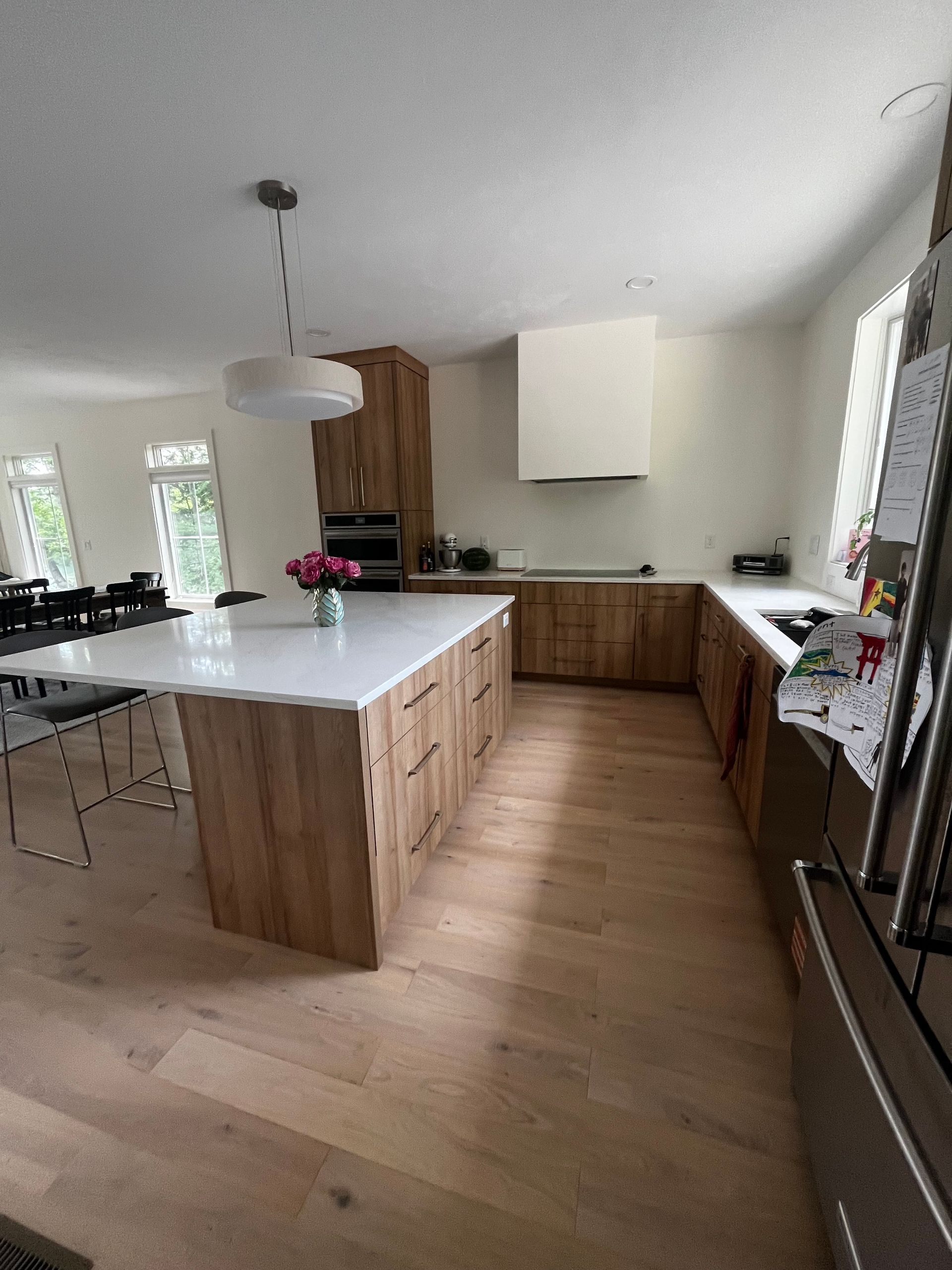 Modern kitchen with a large island, wood cabinets, white countertops, and a bright open layout.