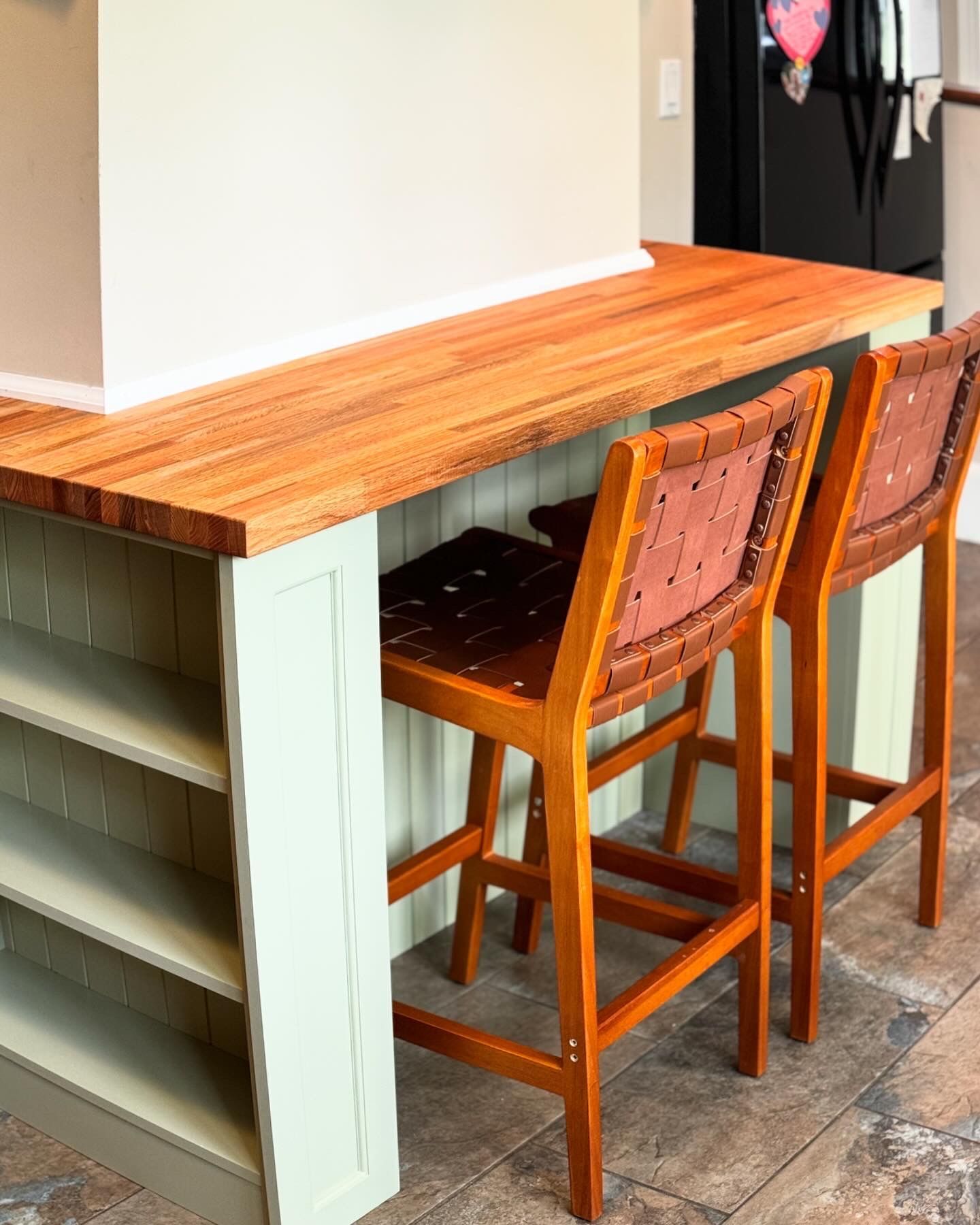 Two wooden bar stools sit at a kitchen island with a wood countertop.