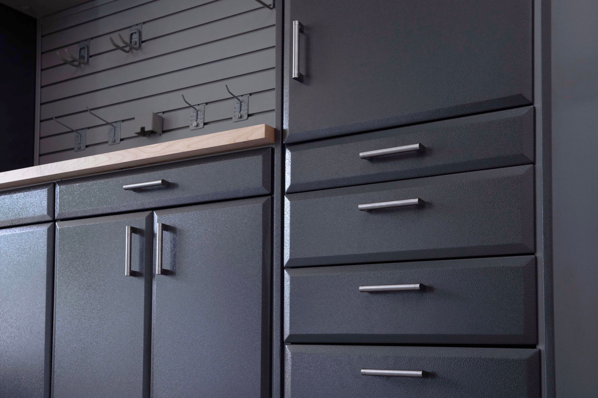 Dark gray cabinetry with drawers and doors, mounted on a wall with hooks.