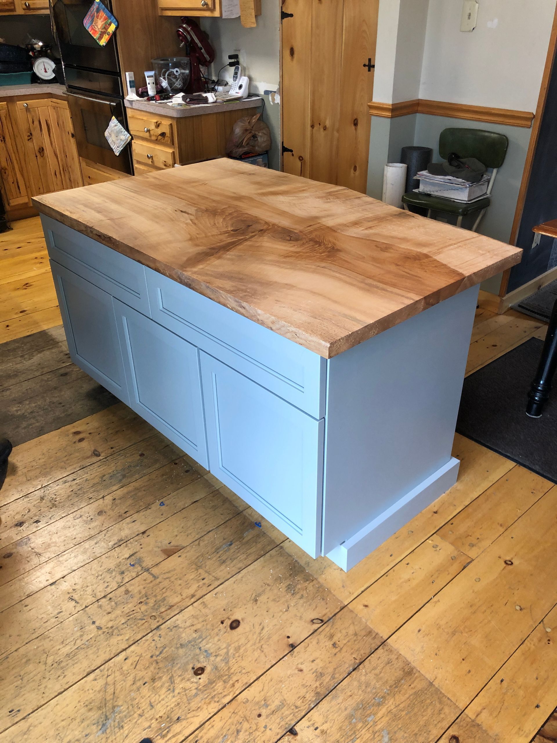 Light blue kitchen island with a wooden countertop on a wood floor.
