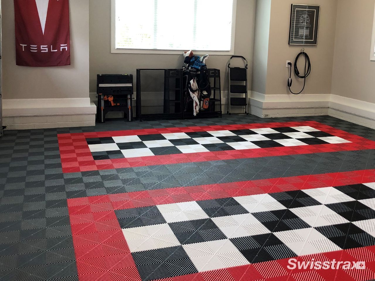 Garage with checkered floor mats and Tesla flag.