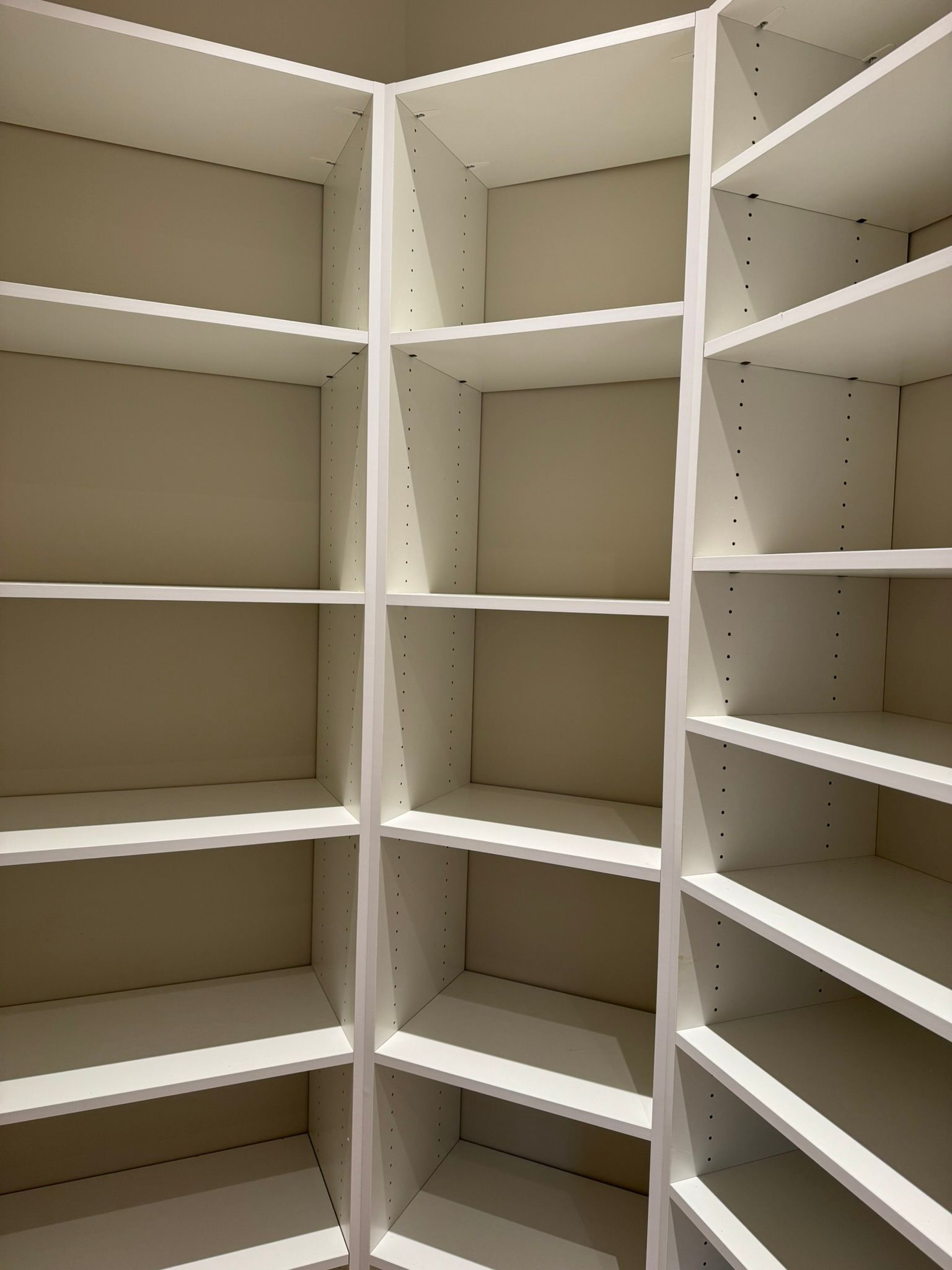 Empty white corner shelving unit.