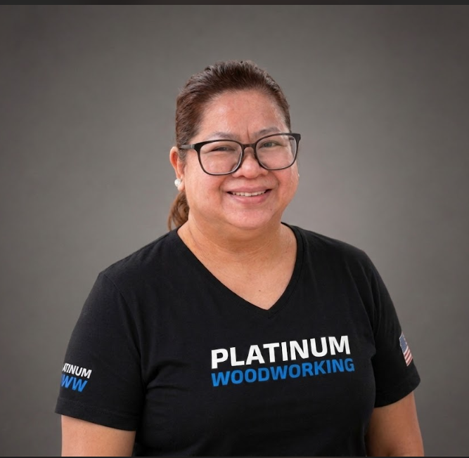Smiling person in glasses wearing a black Platinum Woodworking T-shirt on a gray background