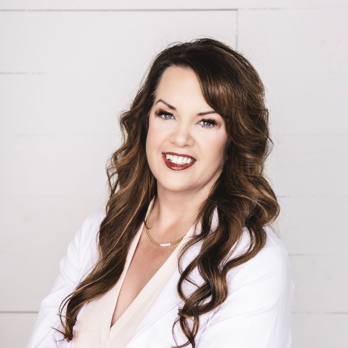 A woman in a white coat is smiling for the camera.