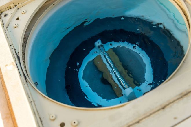 Overhead view of a washing machine drum filled with blue-tinted water and a central agitator.