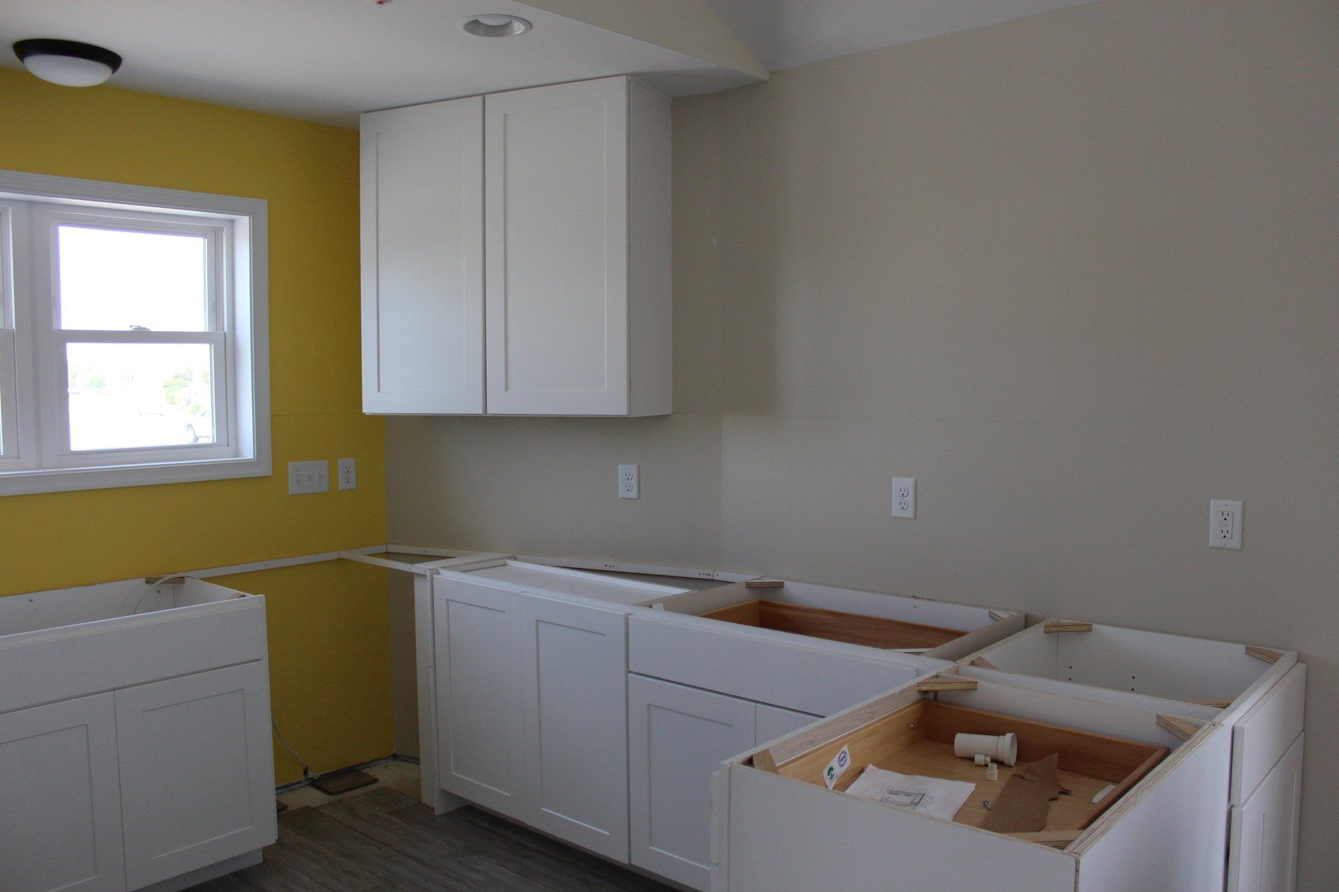 A kitchen under construction with yellow walls and white cabinets
