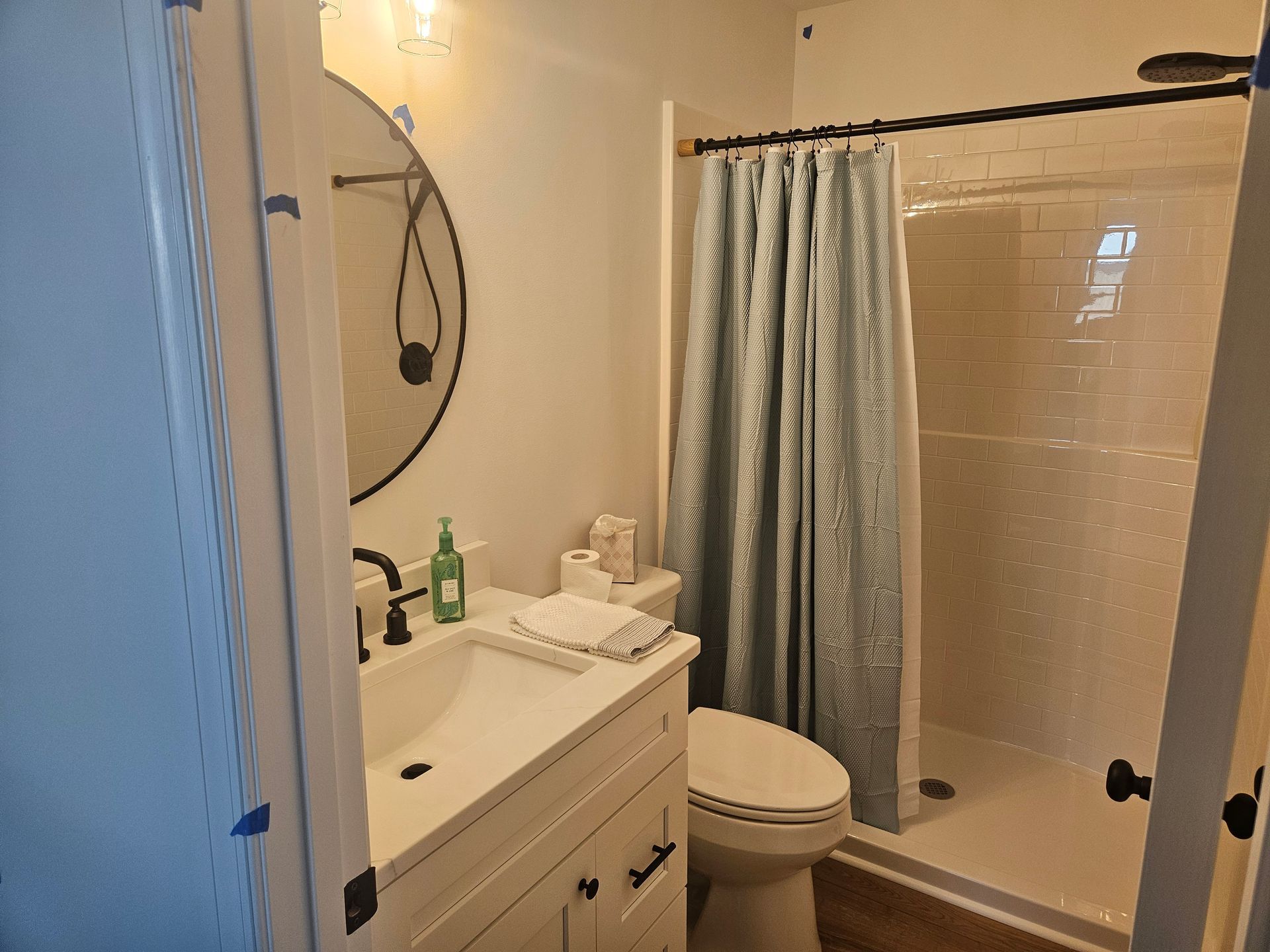 A bathroom with a toilet , sink , mirror and shower