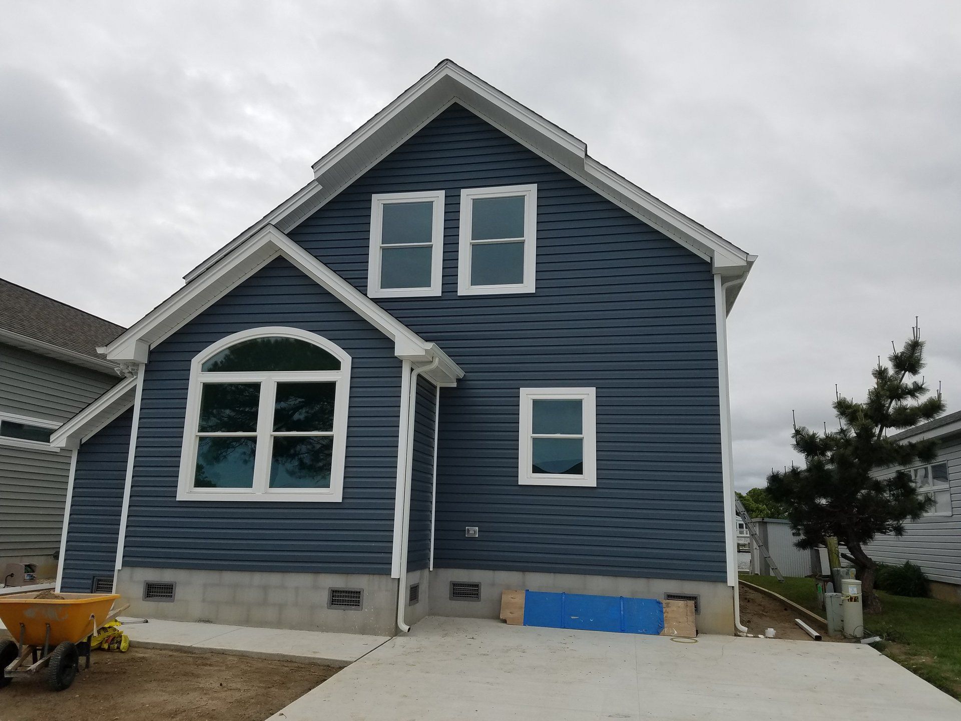 A blue house with a yellow wheelbarrow in front of it