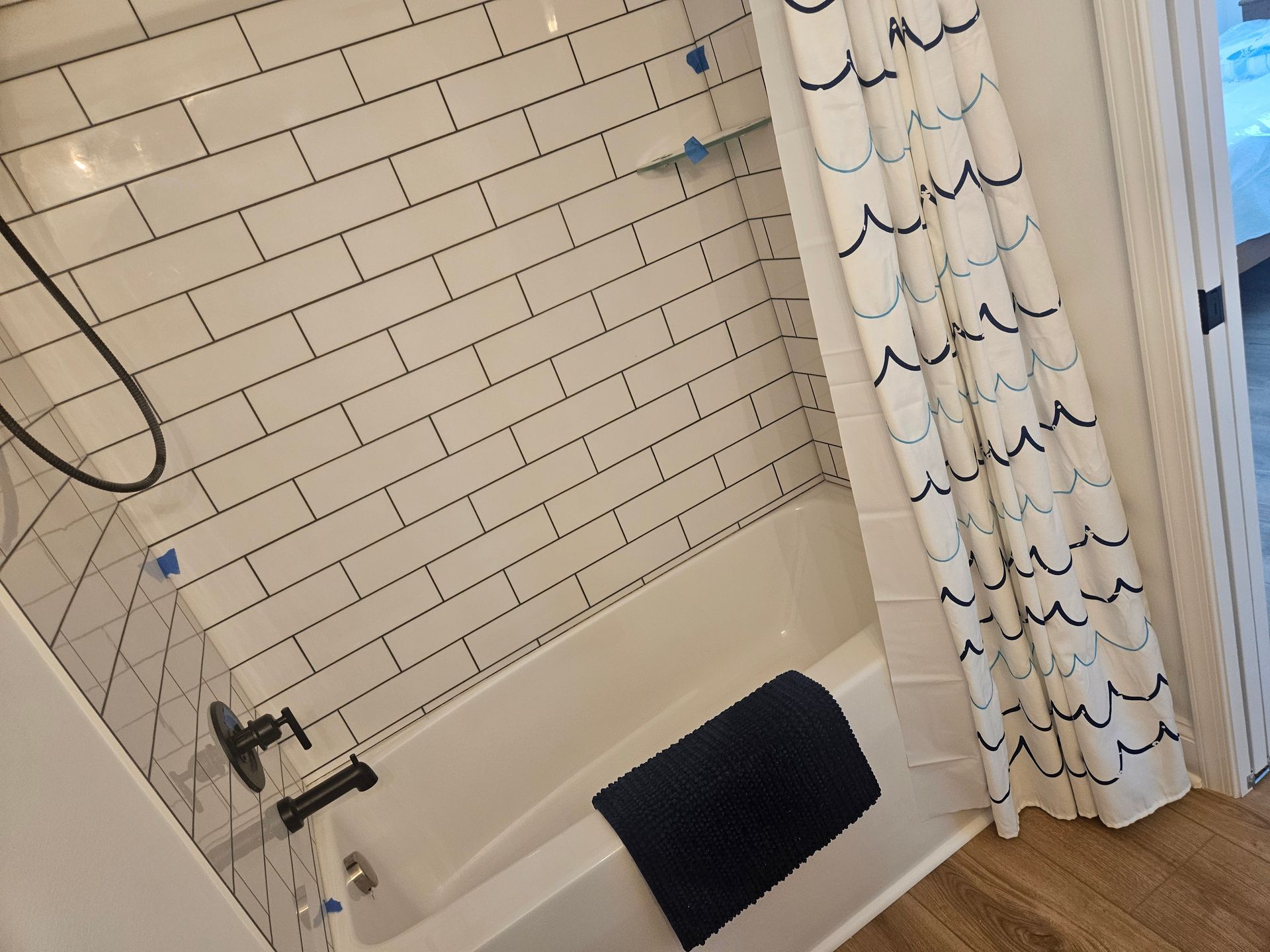 A bathroom with white tiles and a shower curtain