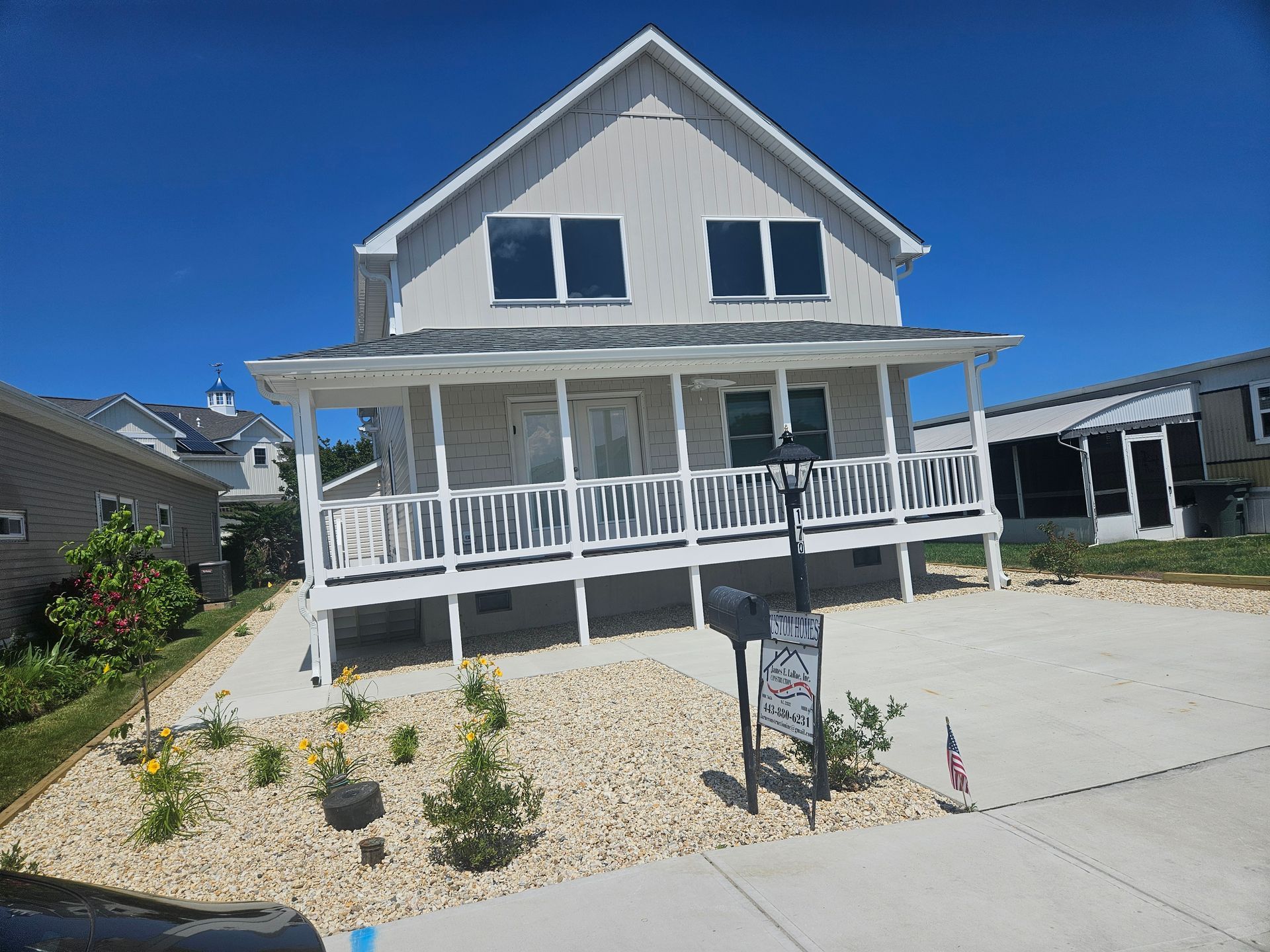 A white house with a large porch and a mailbox in front of it