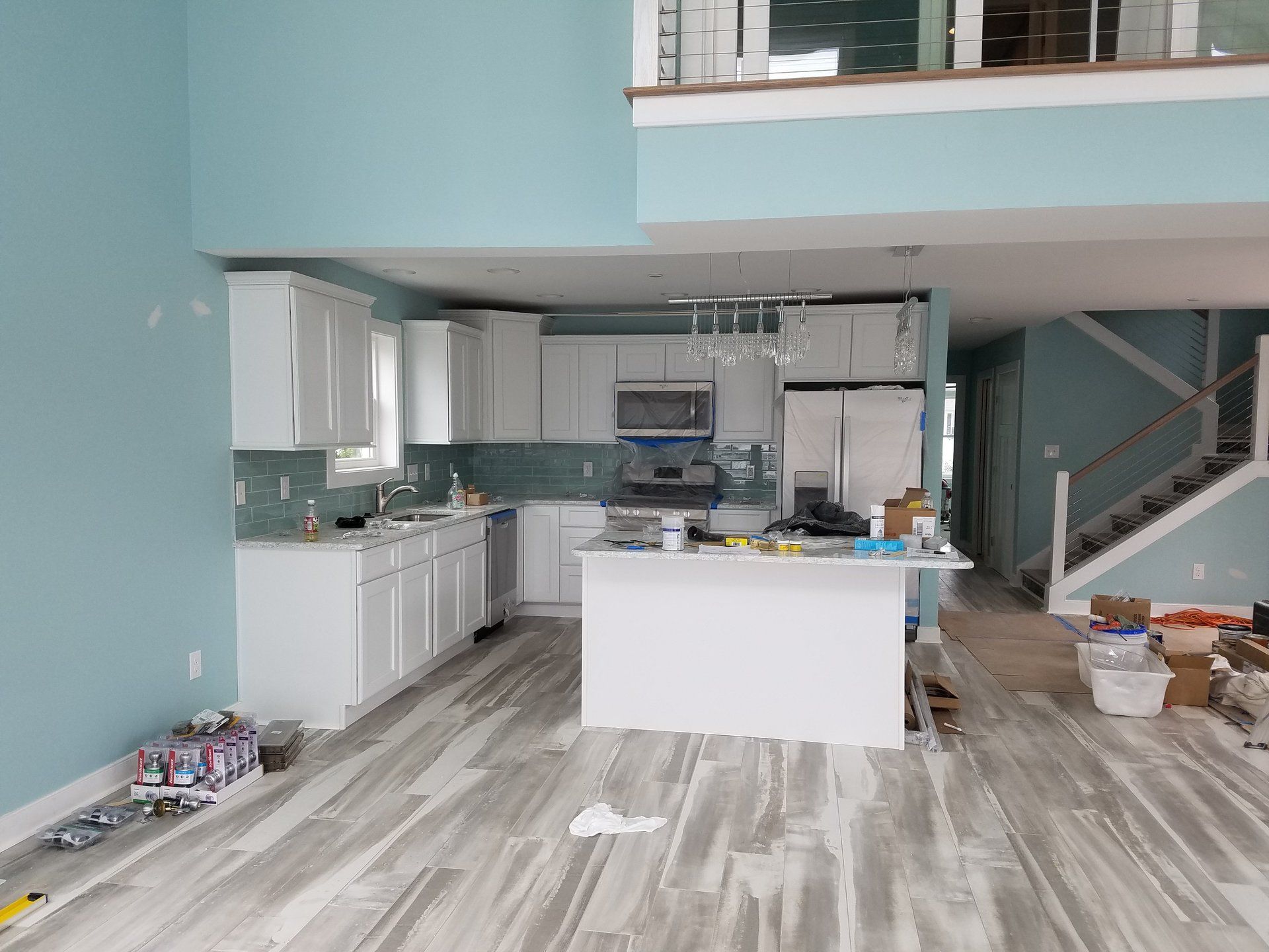 A kitchen with white cabinets and a large island in a house under construction.