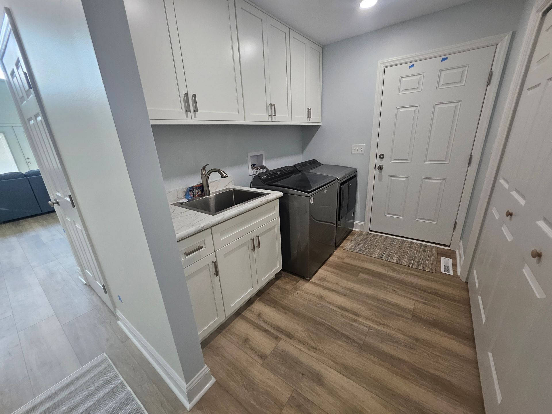 A laundry room with a sink, washer and dryer, and wooden floors