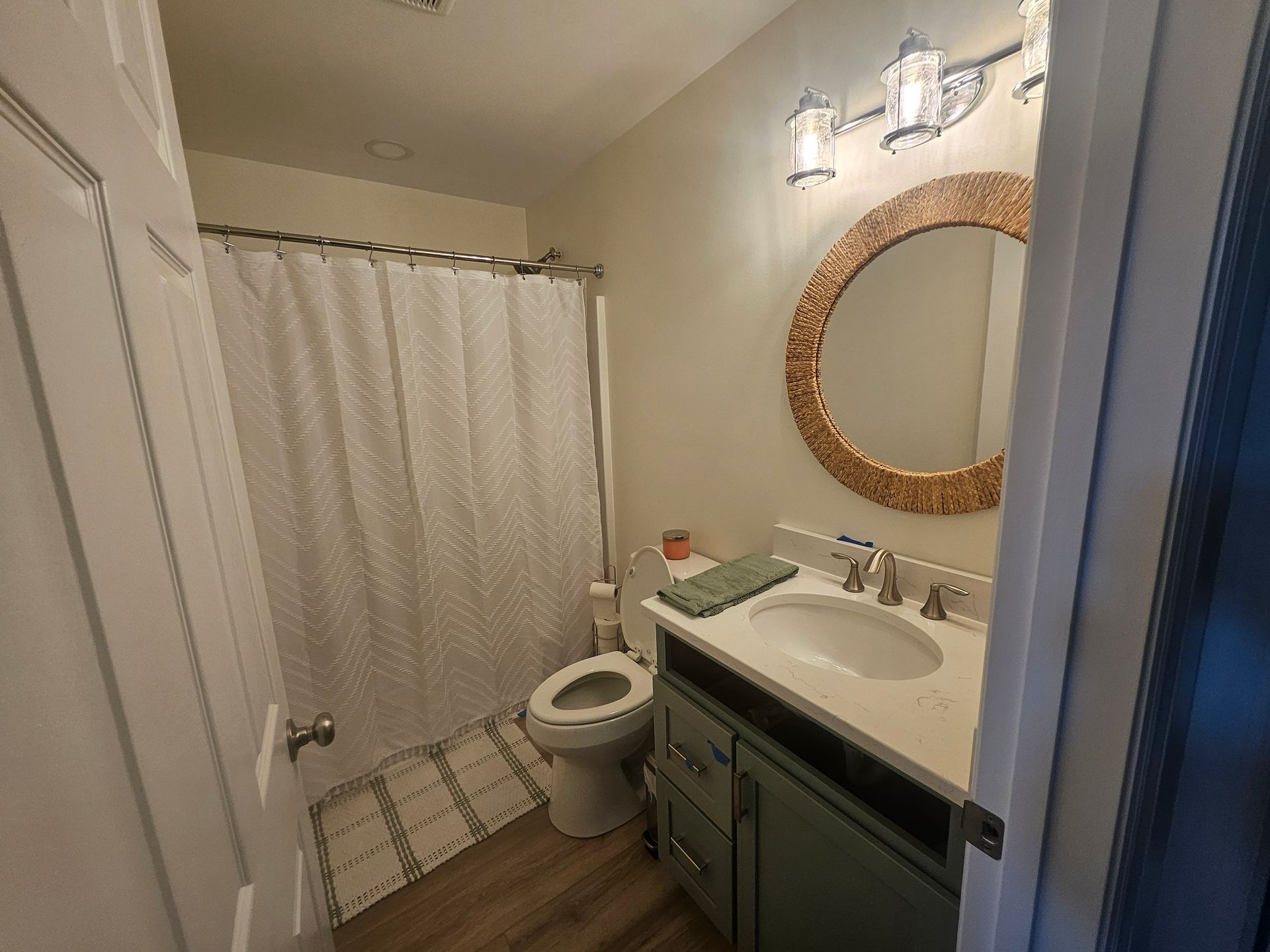 A bathroom with a toilet, sink, mirror and shower curtain